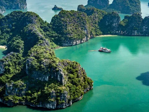 Aerial view of limestone karst islands surrounding turquoise water with two small boats visible in the bay.