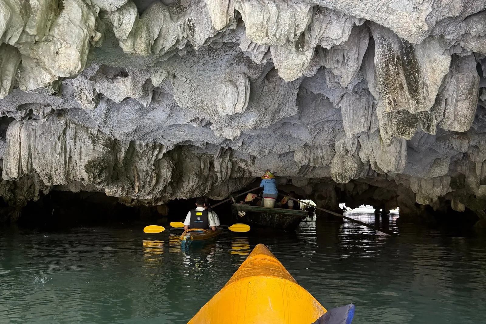 Kayaks paddled in under a cave mouth, the rock ceiling low overhead