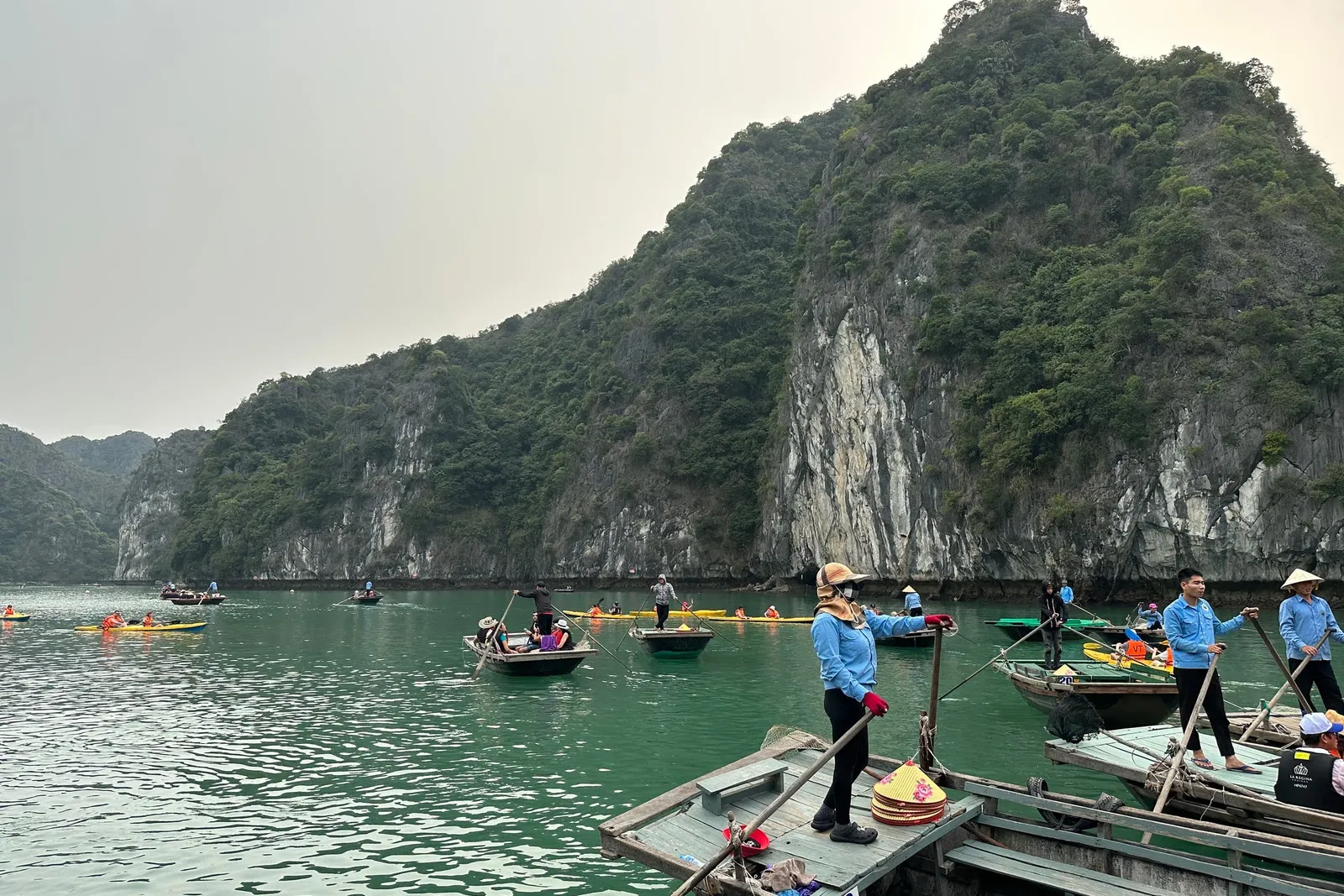 Local rowers in conical hats waiting in their boats to take guests through the karst
