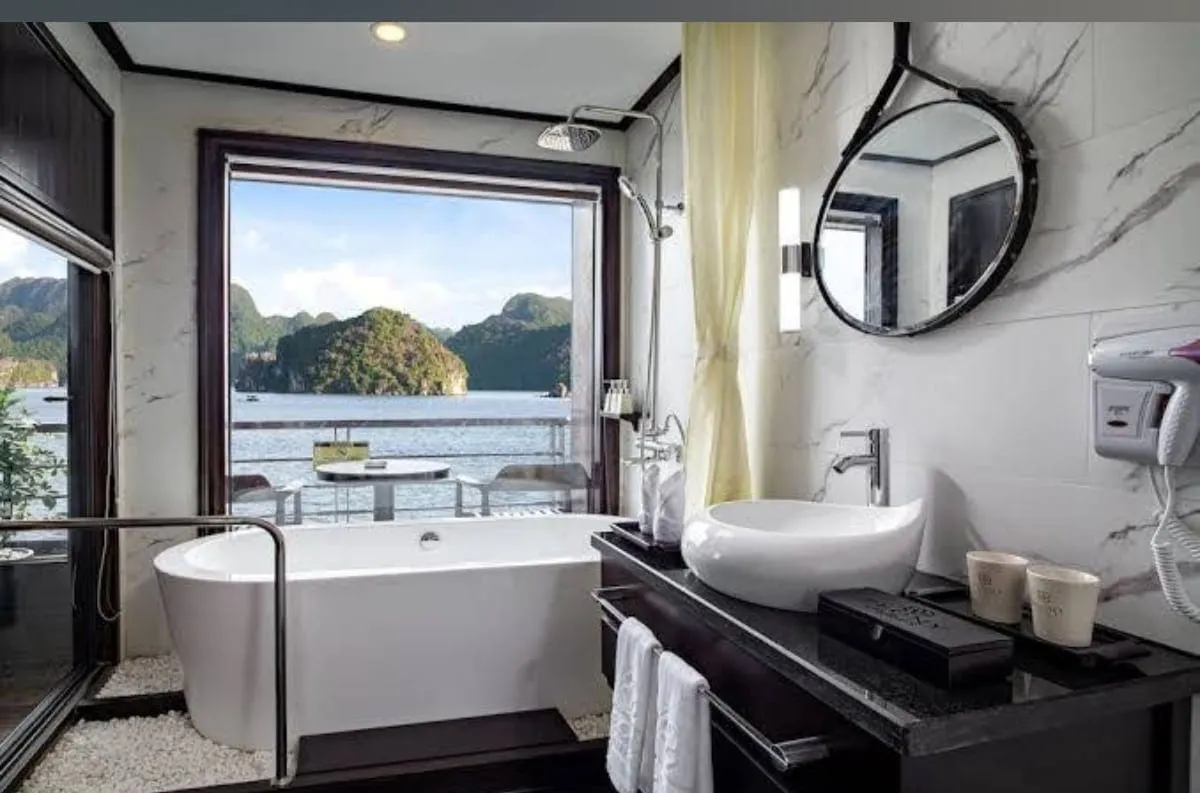 Bathroom in white marble with a freestanding tub under the window and a round mirror over the basin