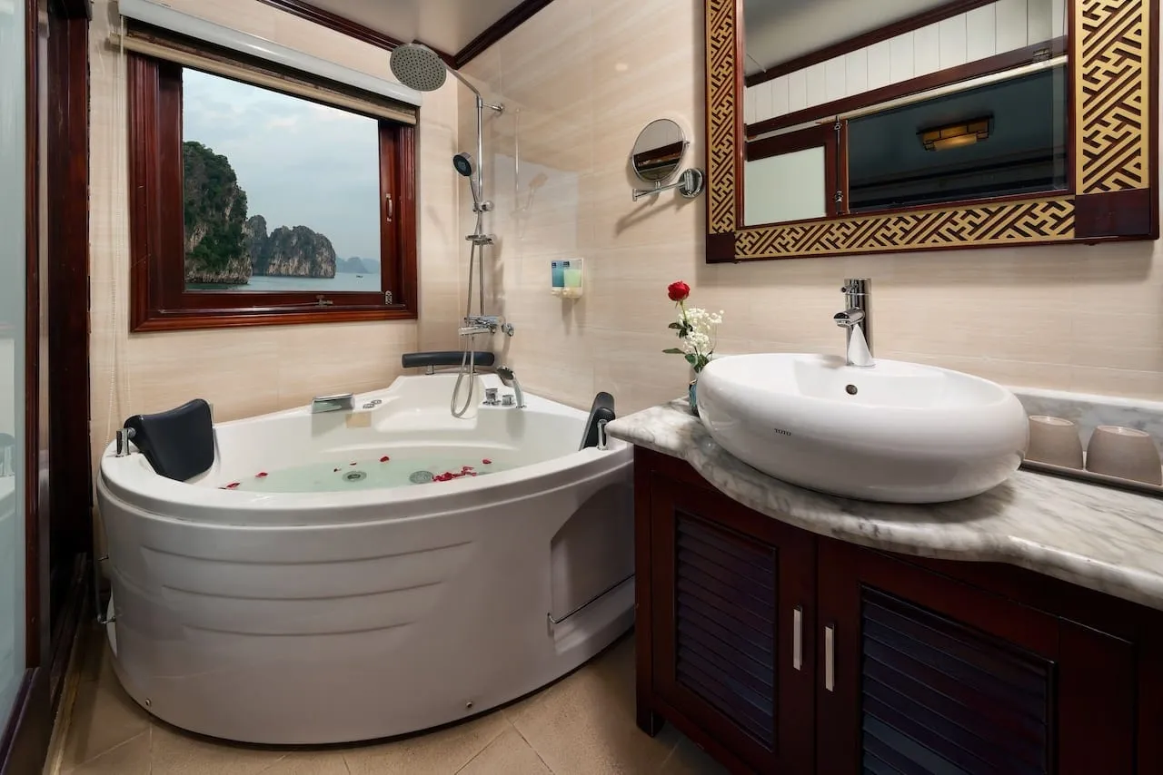 Corner jacuzzi tub beside a stone basin, a window above it looking out at the karst