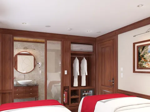 A boat cabin interior with two beds, wood paneling, an ensuite bathroom visible through glass, hanging robes, and a framed painting on the wall.