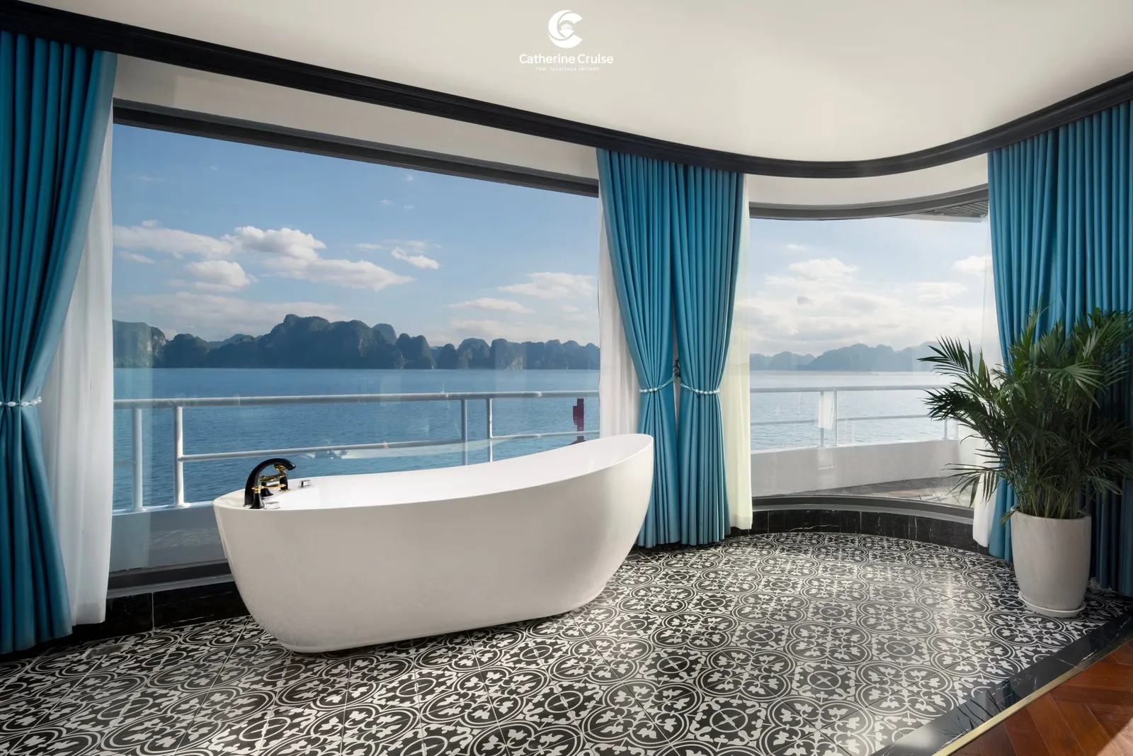 Freestanding bath set on a patterned tile floor in front of full-height windows onto the bay