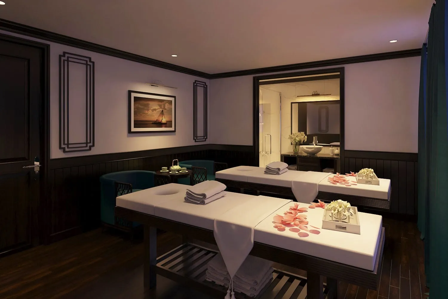 A spa treatment room with two massage beds, folded towels, flower petals, seating area, and an ensuite bathroom visible through a doorway.