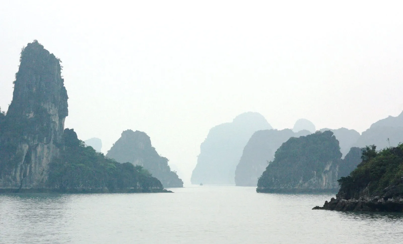 Limestone islands fading into haze across calm water