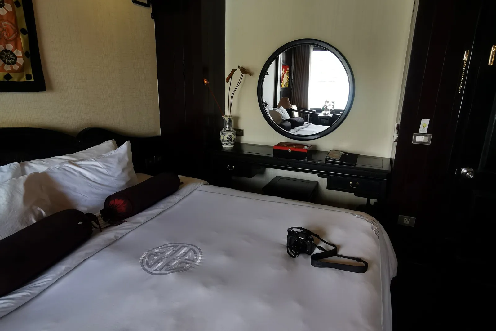 Cabin with a round mirror above the desk, dark timber panelling and a lamp beside the bed