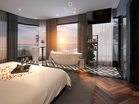 Suite with a freestanding bath by the window, petals laid on the bed and a tray of glasses at its foot
