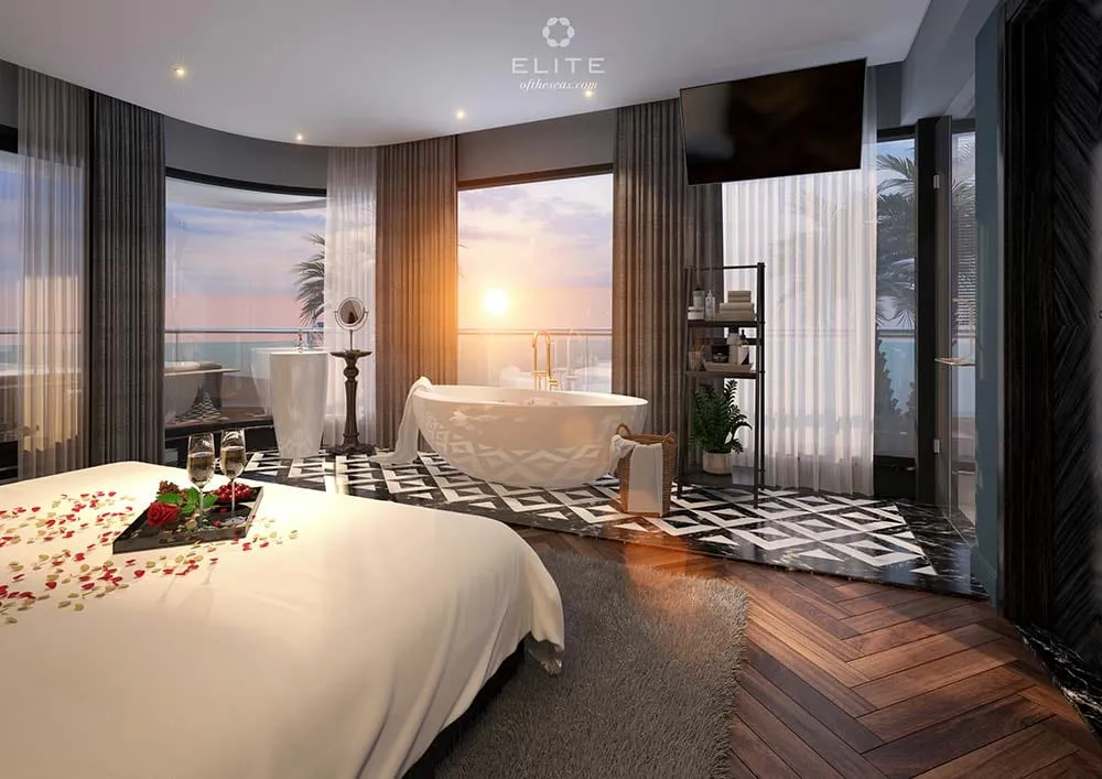 Suite with a freestanding bath by the window, petals laid on the bed and a tray of glasses at its foot