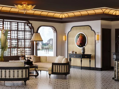 An elegant interior cabin lounge with ornate lighting, decorative screens, cream upholstered furniture, and a window view showing karst limestone formations on the water.