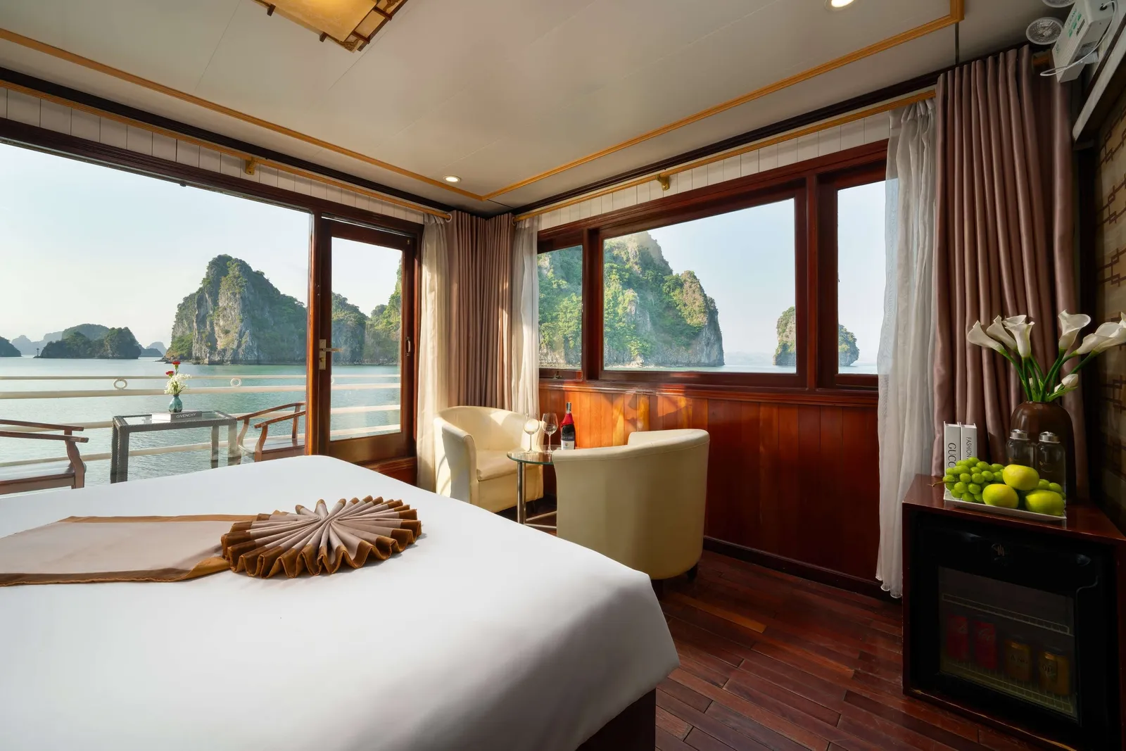 Cabin with a towel fan folded on the bed, an armchair by the corner window and karst filling the glass