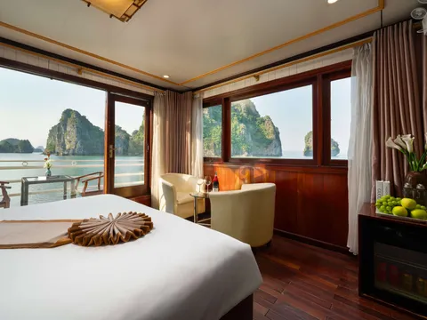 Cabin with a towel fan folded on the bed, an armchair by the corner window and karst filling the glass