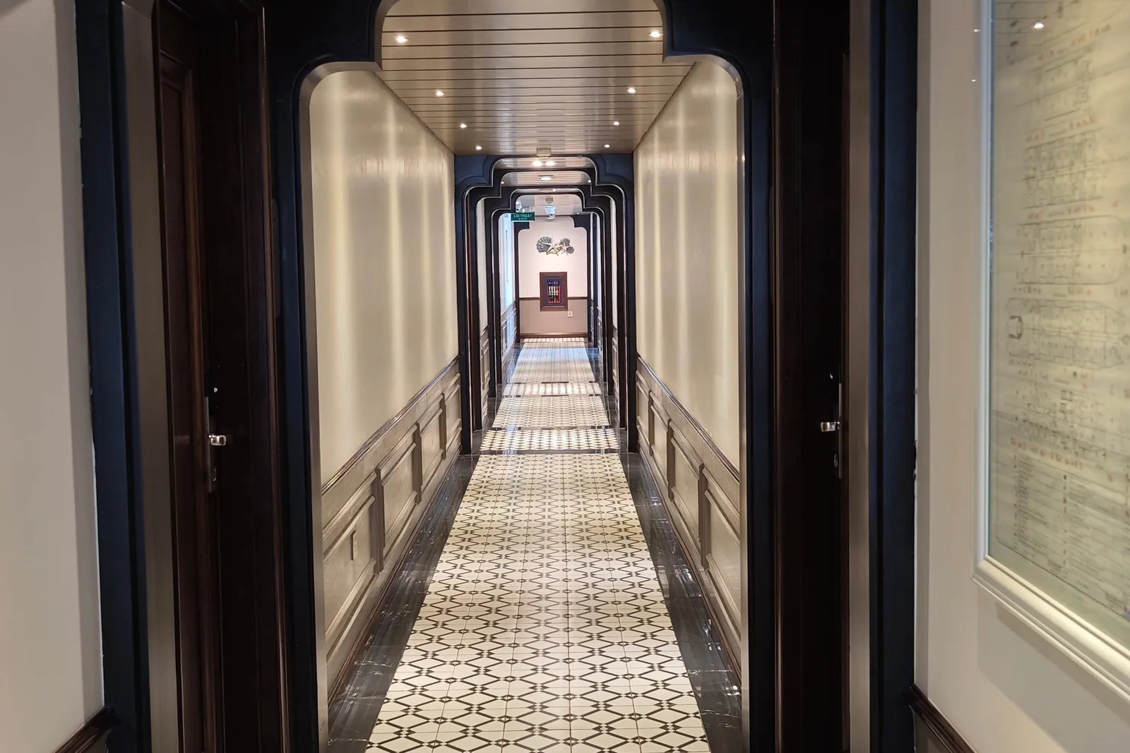 Cabin corridor running the length of the deck, patterned tile floor and panelled doors either side