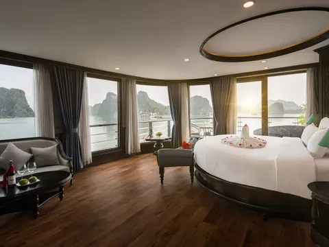 A luxury cruise ship cabin with curved windows showing limestone karst islands in the bay outside.