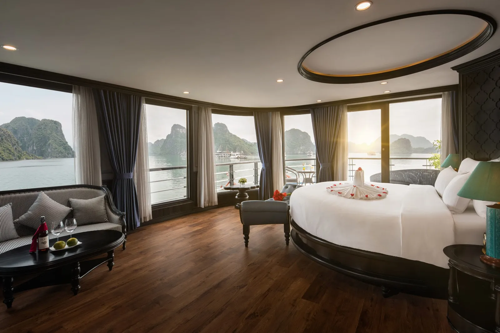 A luxury cruise ship cabin with curved windows showing limestone karst islands in the bay outside.