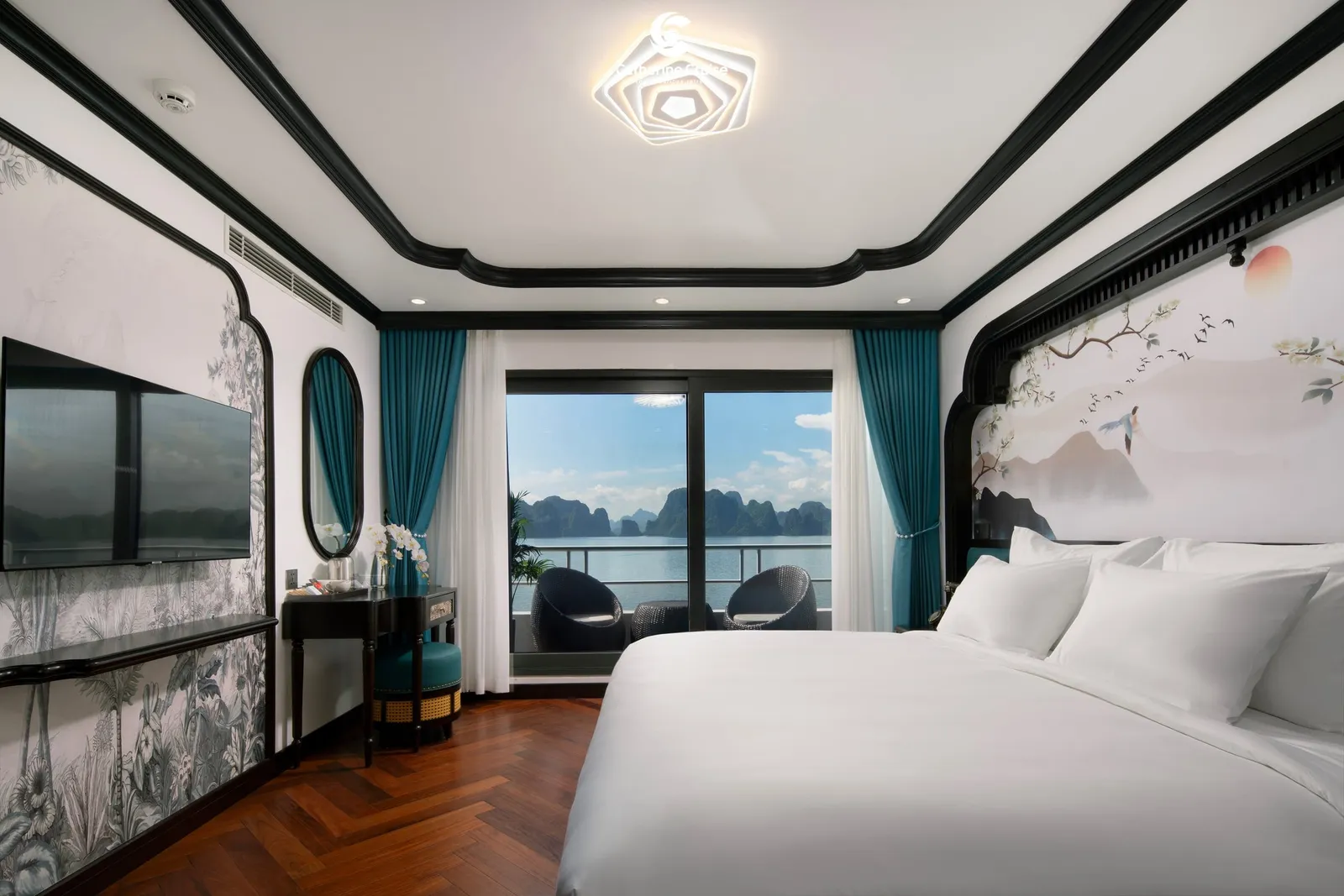 Suite with teal drapes drawn back from a wall of glass, a desk along one side and the bay outside