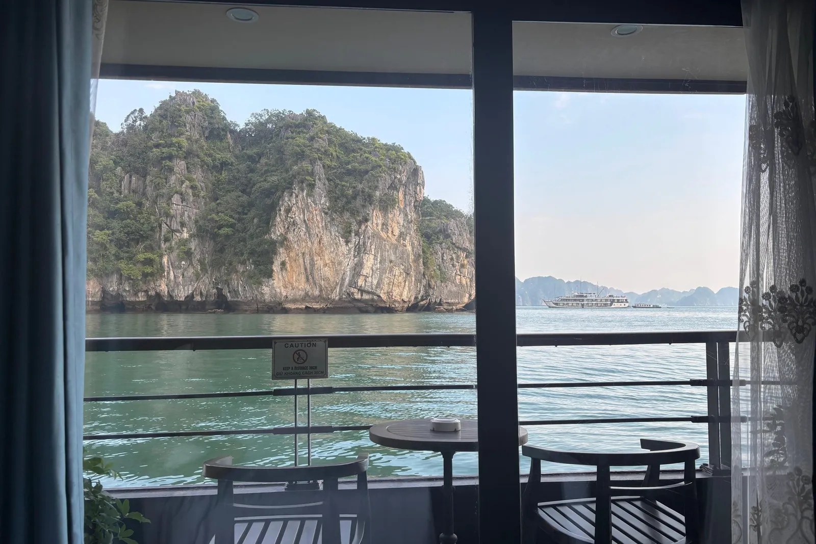 Cabin balcony with two chairs and a low table, karst cliffs framed through the opening