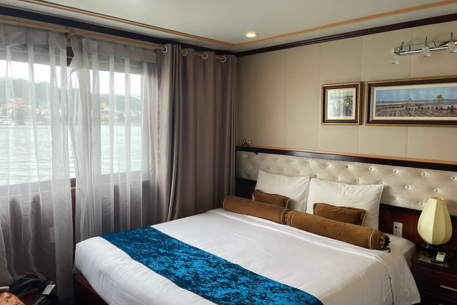 Twin-bed cabin with a tufted headboard and a teal runner, curtains drawn back from the window