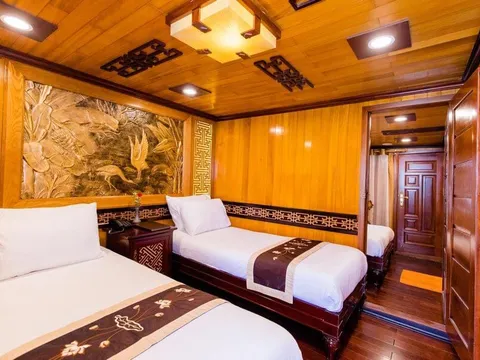 A wooden cabin interior with two beds, decorative carved wall panel, and traditional Asian geometric patterns on the trim.
