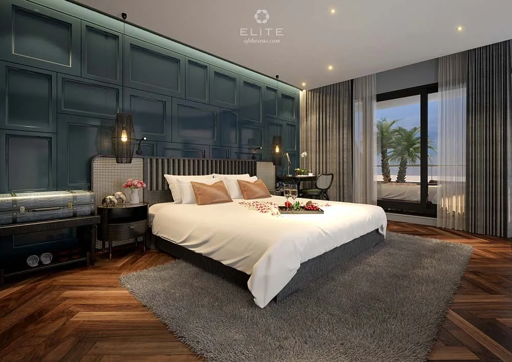 Cabin panelled in deep green with a herringbone floor, the balcony door open to the water