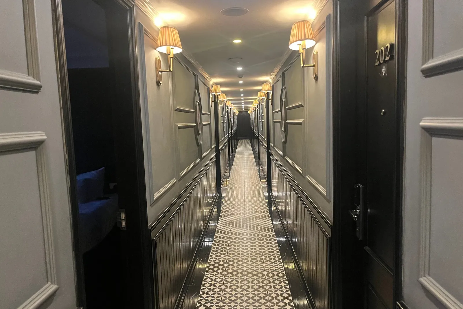 Cabin corridor lit by wall lamps down both sides, patterned runner leading to the far end