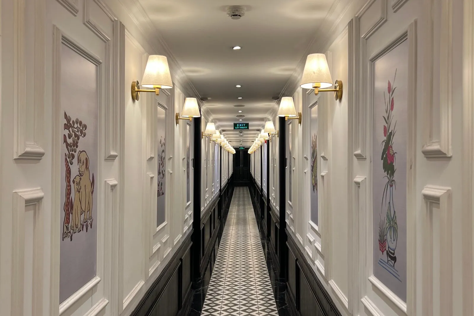 Cabin corridor lit by wall lamps, framed prints between the doors and a patterned runner underfoot