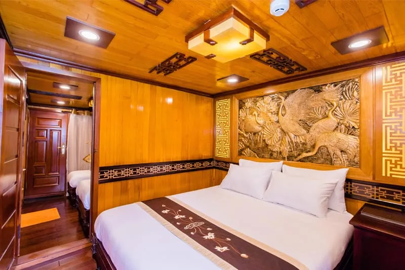 A wooden cabin interior with a double bed, decorative dragon relief on the wall, and warm lighting from ceiling fixtures.