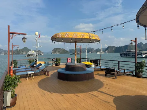 Sundeck with a round jacuzzi under a gold parasol, loungers set out and other cruise boats at anchor beyond