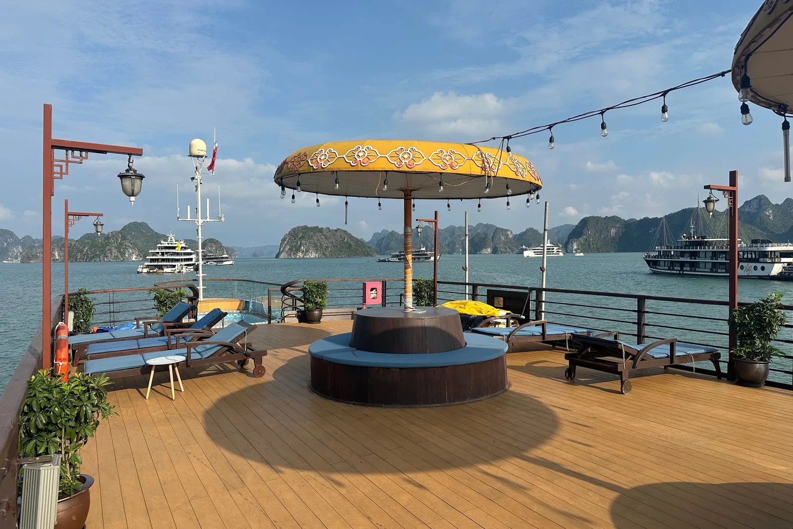 Sundeck with a round jacuzzi under a gold parasol, loungers set out and other cruise boats at anchor beyond