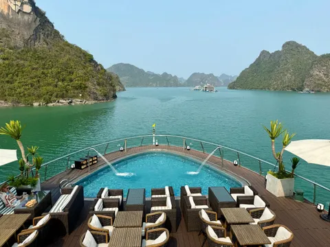Sundeck pool with loungers along both sides and potted palms at the rail, the bay opening out beyond