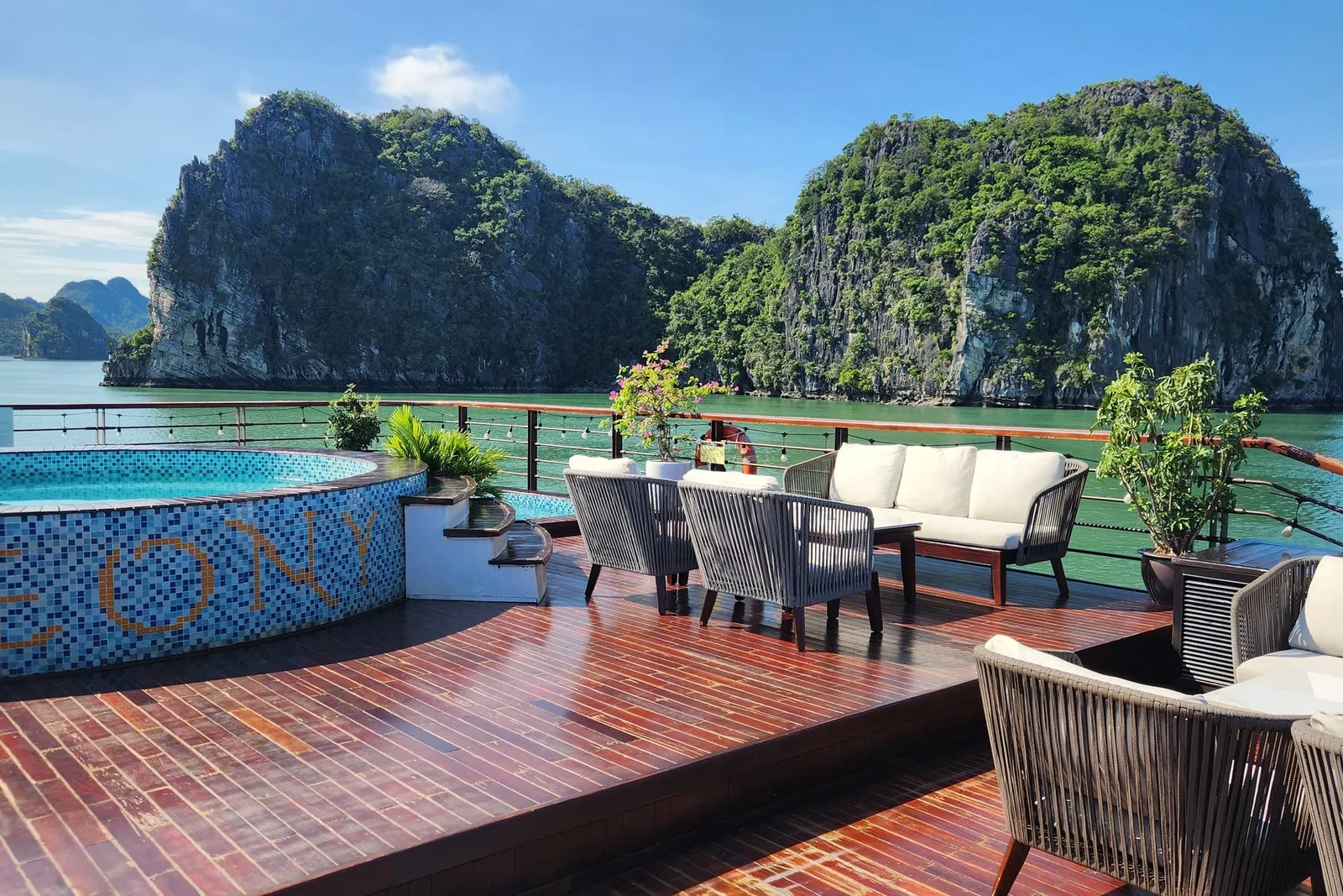 Sundeck pool set into a timber deck, cushioned seating along one side and a karst wall rising straight out of the water beyond
