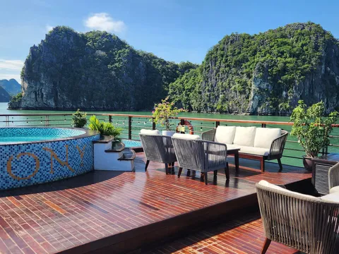Sundeck pool set into a timber deck, cushioned seating along one side and a karst wall rising straight out of the water beyond
