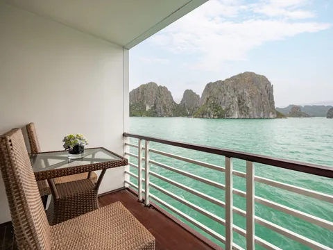 A private balcony with wicker furniture overlooking turquoise water and dramatic limestone karst formations.