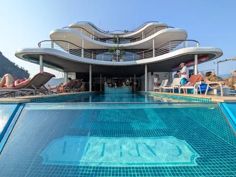 Sundeck pool with the ship name set into the tiled floor, loungers along both sides and the curved white superstructure above