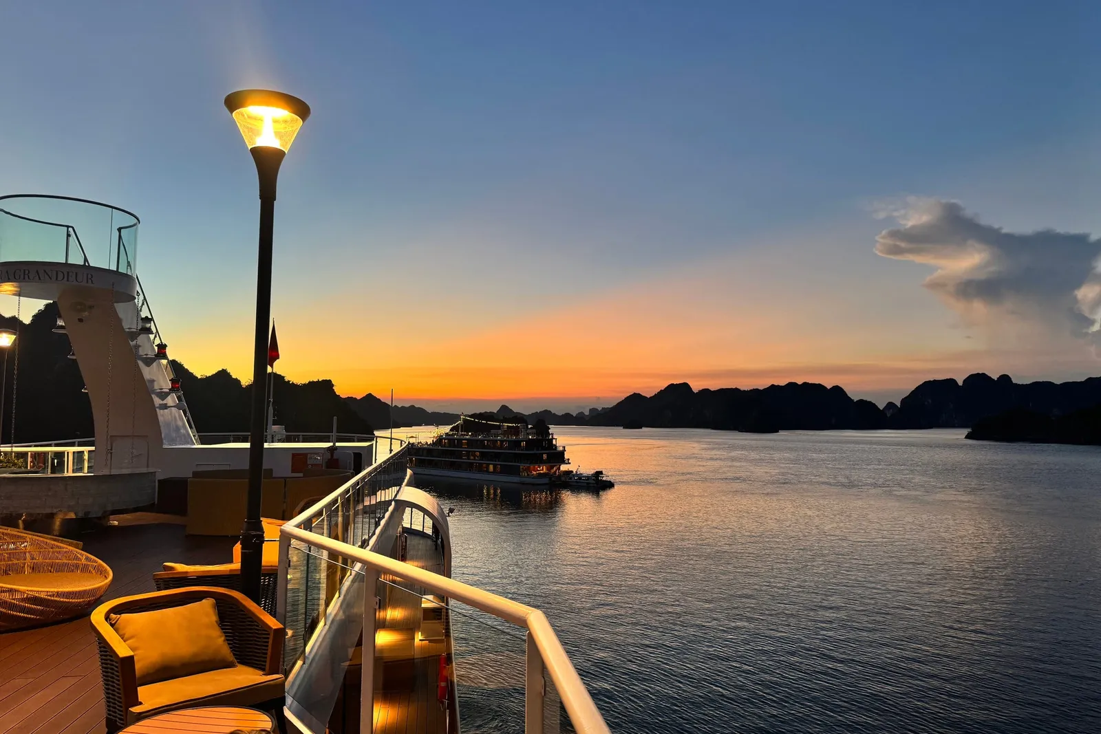 Deck seating at dusk under a lamp, the last light going off the water behind the rail