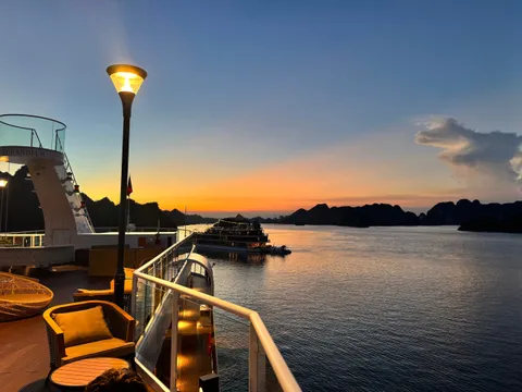 Deck seating at dusk under a lamp, the last light going off the water behind the rail