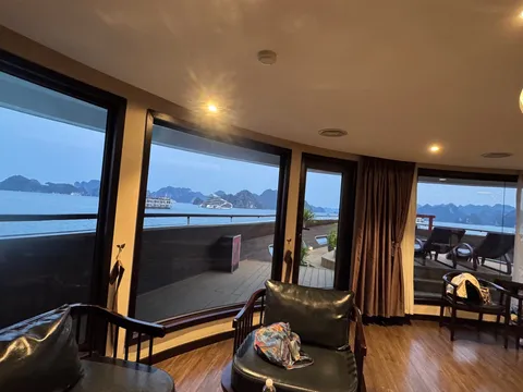 Glass-walled lounge running the width of the ship, timber floor and armchairs turned to the view