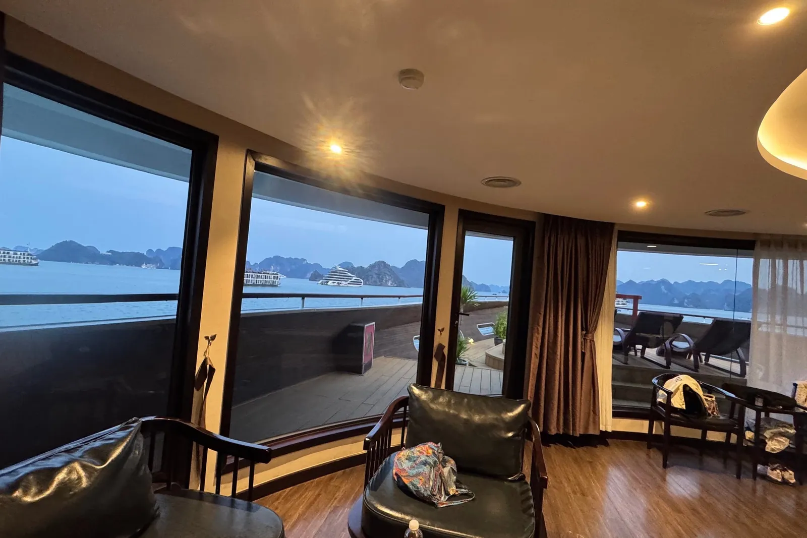 Glass-walled lounge running the width of the ship, timber floor and armchairs turned to the view
