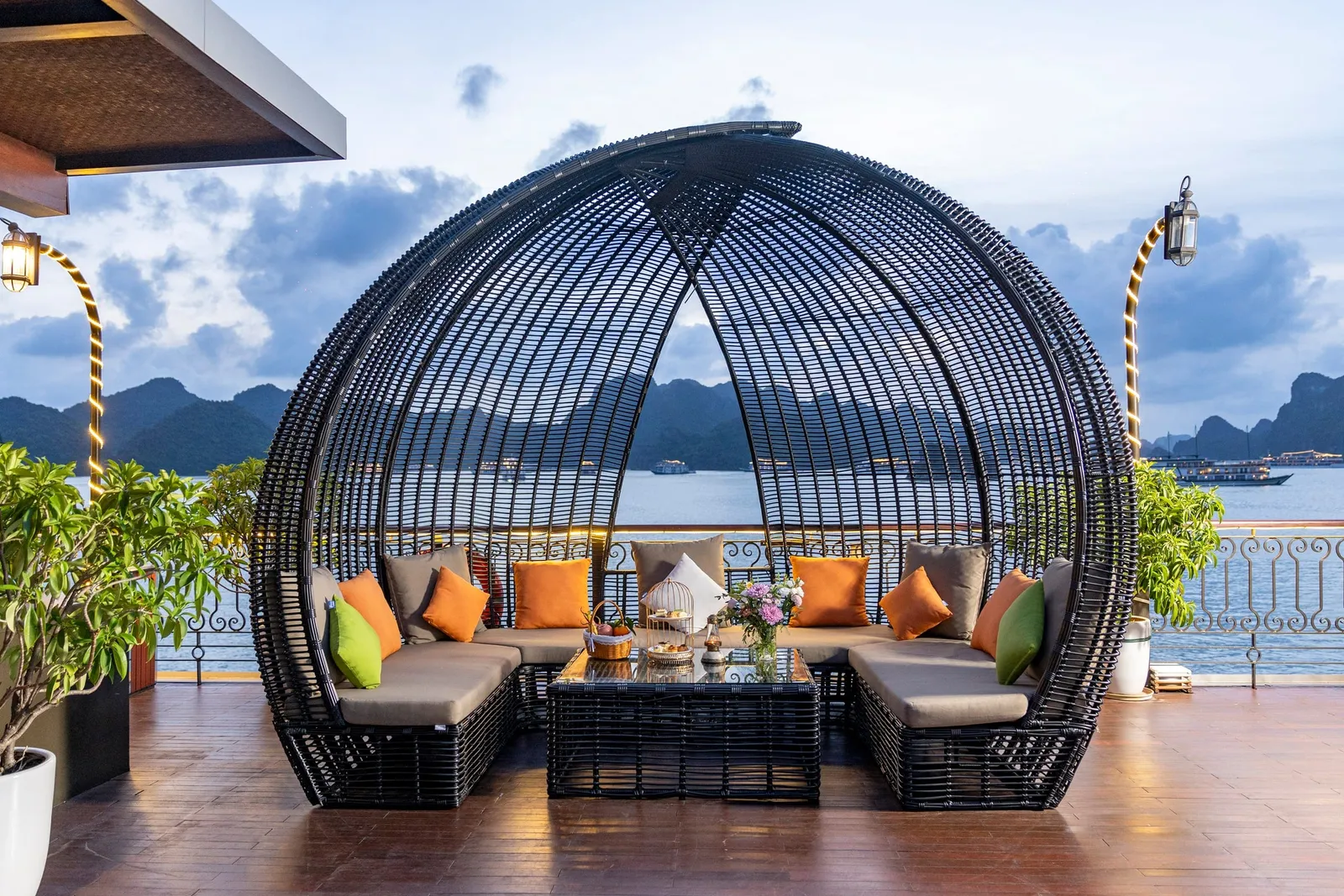 Rattan pod seat on the deck, cushioned and open to the bay, potted plants either side