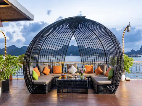 Rattan pod seat on the deck, cushioned and open to the bay, potted plants either side