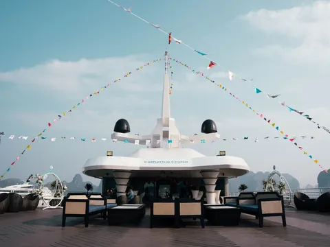 Top deck dressed with signal flags running from the mast, loungers along both sides, calm water beyond