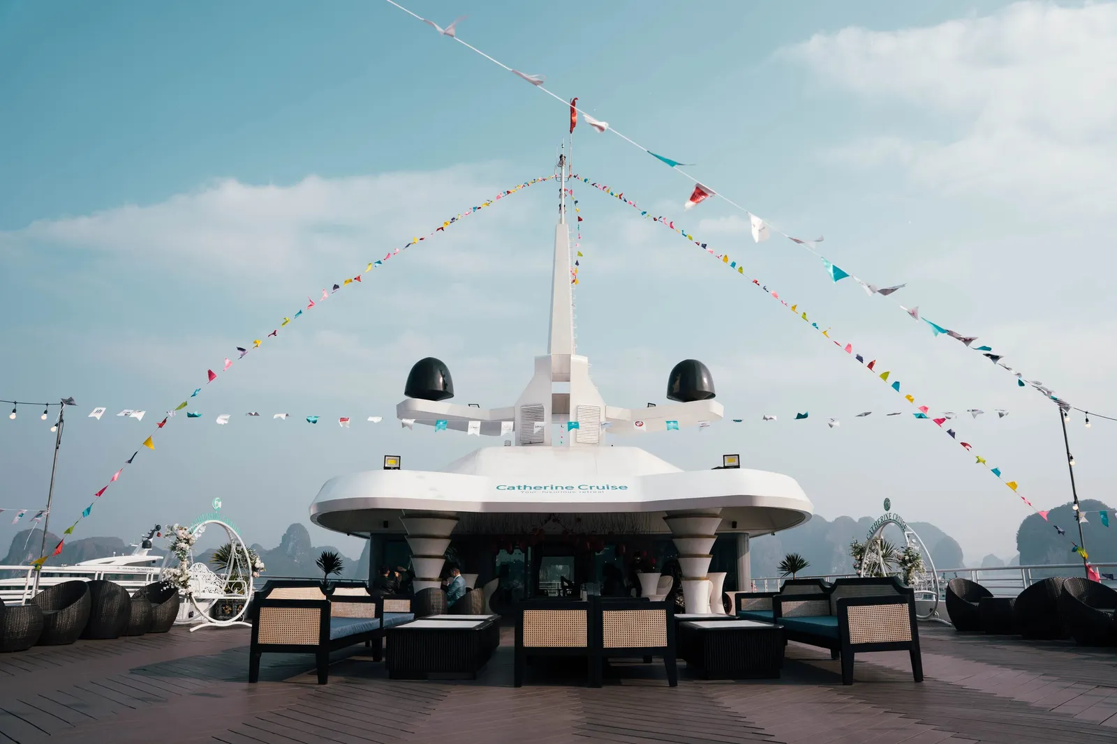Top deck dressed with signal flags running from the mast, loungers along both sides, calm water beyond