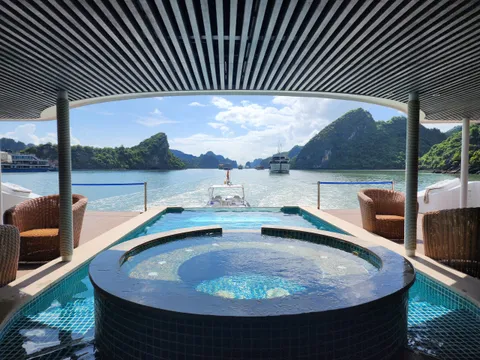 Jacuzzi and pool under a slatted canopy, looking straight out through the opening at karst islands