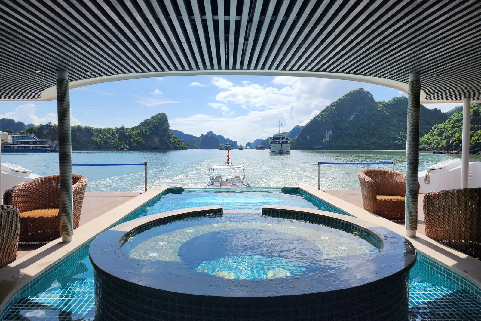 Jacuzzi and pool under a slatted canopy, looking straight out through the opening at karst islands
