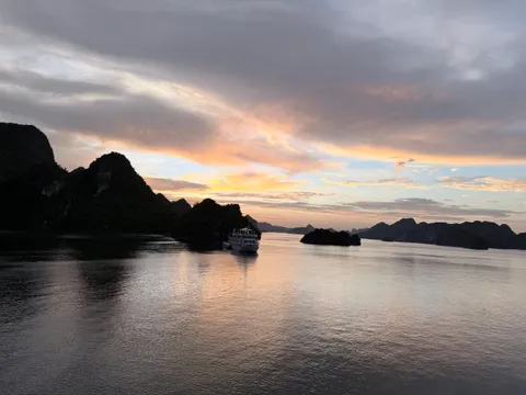 Sunset from the deck, a single boat out on flat water and the karst flattened to silhouettes