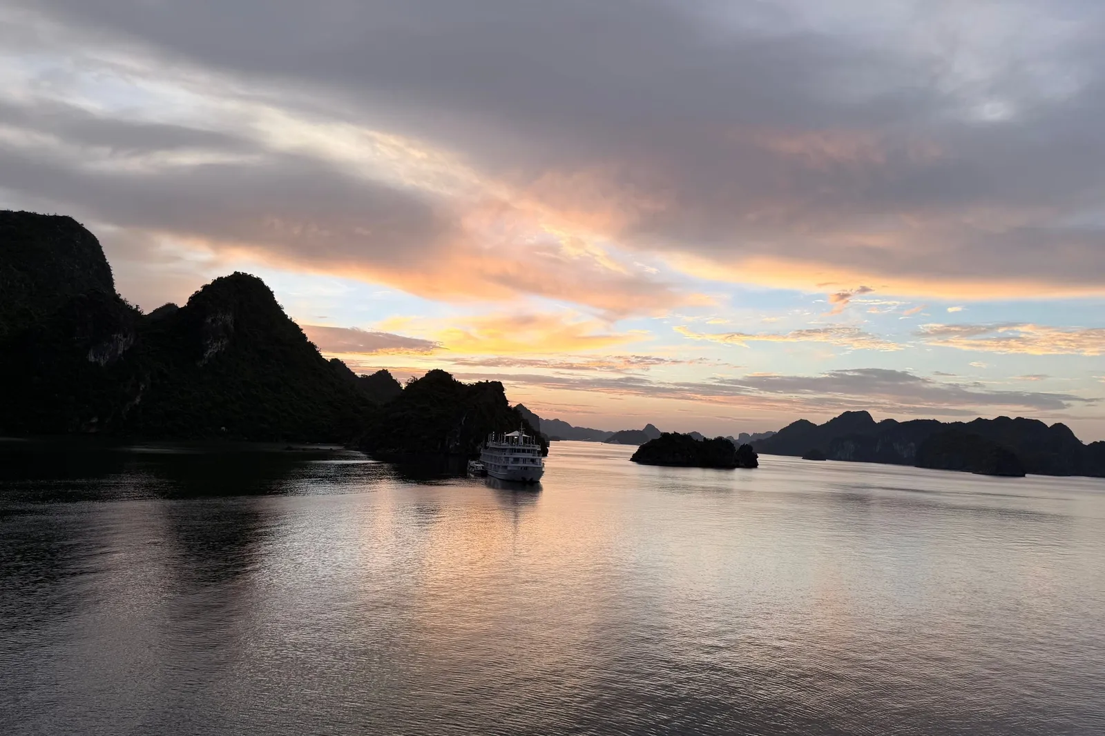 Sunset from the deck, a single boat out on flat water and the karst flattened to silhouettes