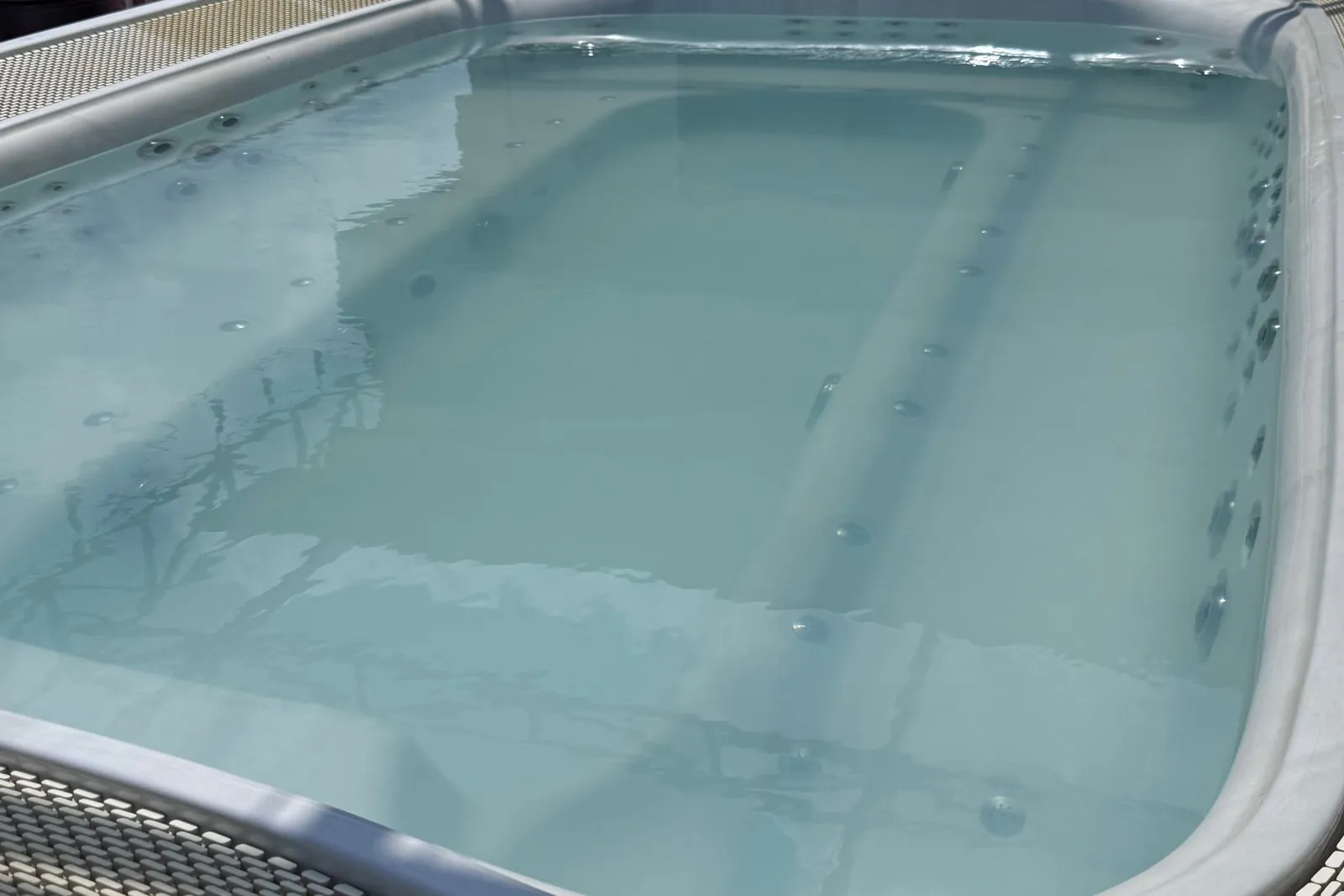 A jacuzzi on the sun deck of a ship, with a bar behind it bearing gold lettering 'HERMES B...' and limestone karst islands over the water in the background.