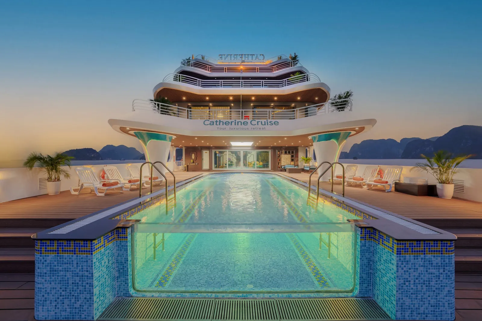 Deck pool running the width of the ship, loungers along both sides and the tiered white decks rising behind