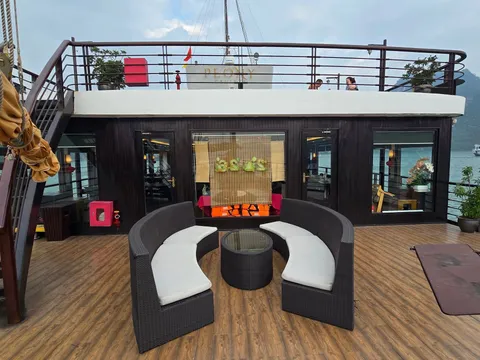 Upper deck lounge with curved rattan seats around a low table, the mast and bridge behind