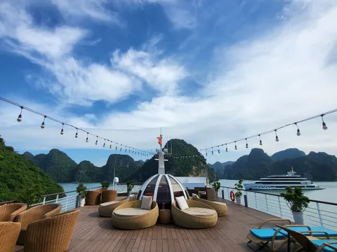 Timber deck with a domed daybed and string lights strung overhead, karst islands beyond the rail