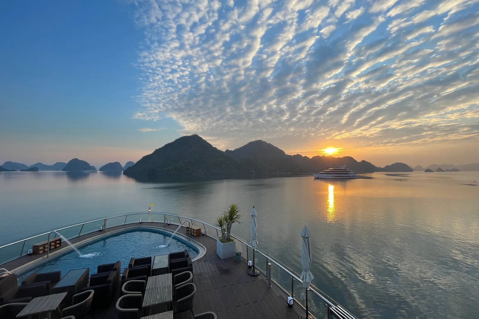 Sunrise seen from the top deck, loungers in the foreground and a mackerel sky over the bay